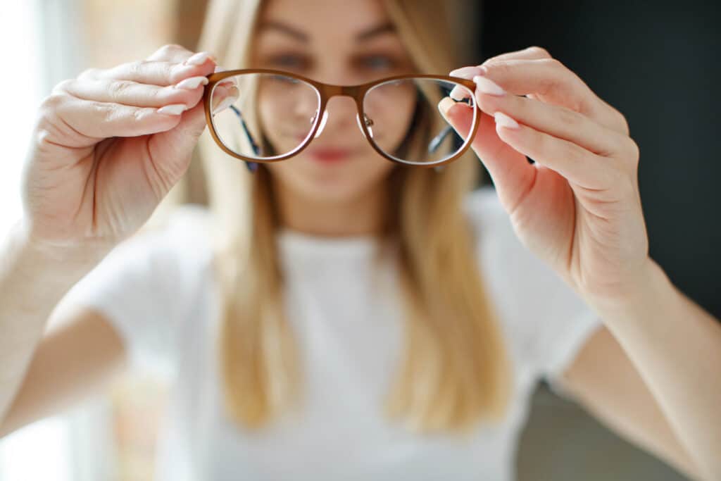 Girl holds glasses for sight in her hands.