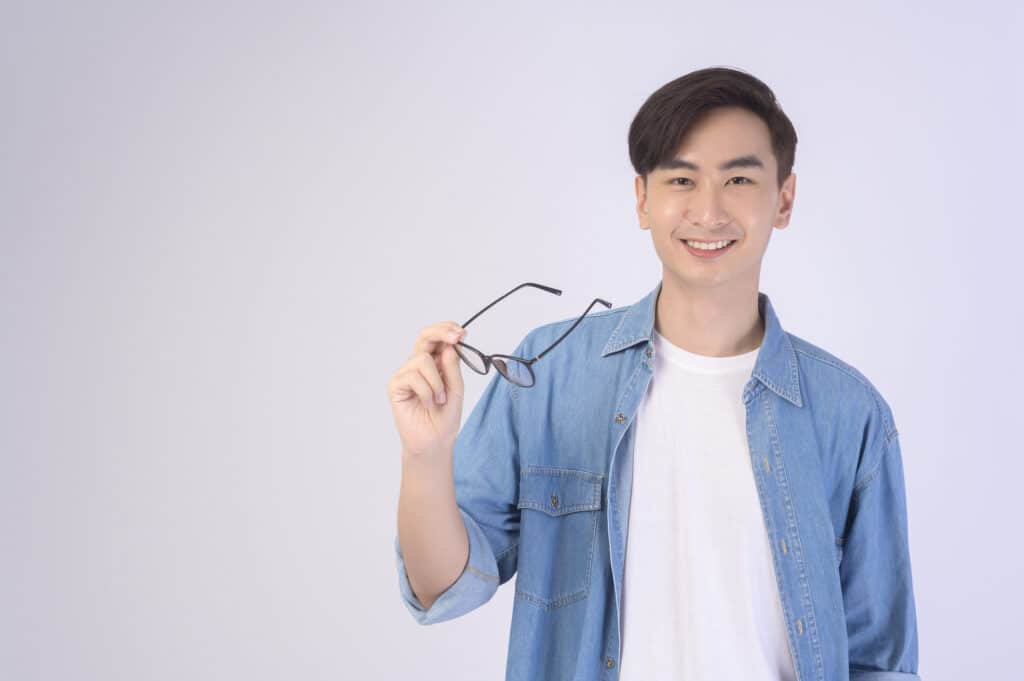 Portrait of asian man wearing glasses over white background studio, eyecare concept.