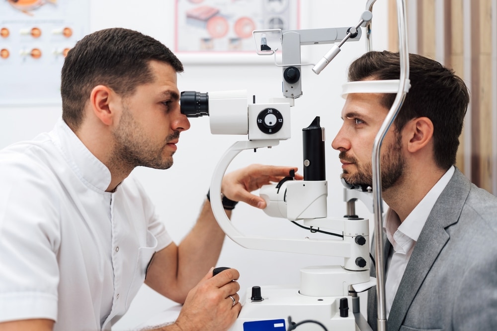 Male ophthalmologist checking the eye vision of a middle-aged man during a monovision LASIK consultation in a modern clinic.