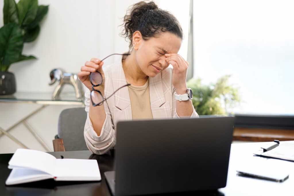 Woman experiencing eye discomfort and vision problems while working on a computer.